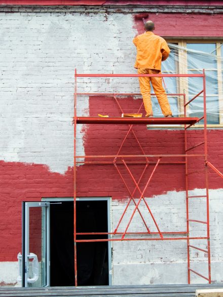 Painting in red Man painting a brick wall in red